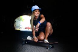 woman crouching while riding on skateboard during daytime shallow focus photography