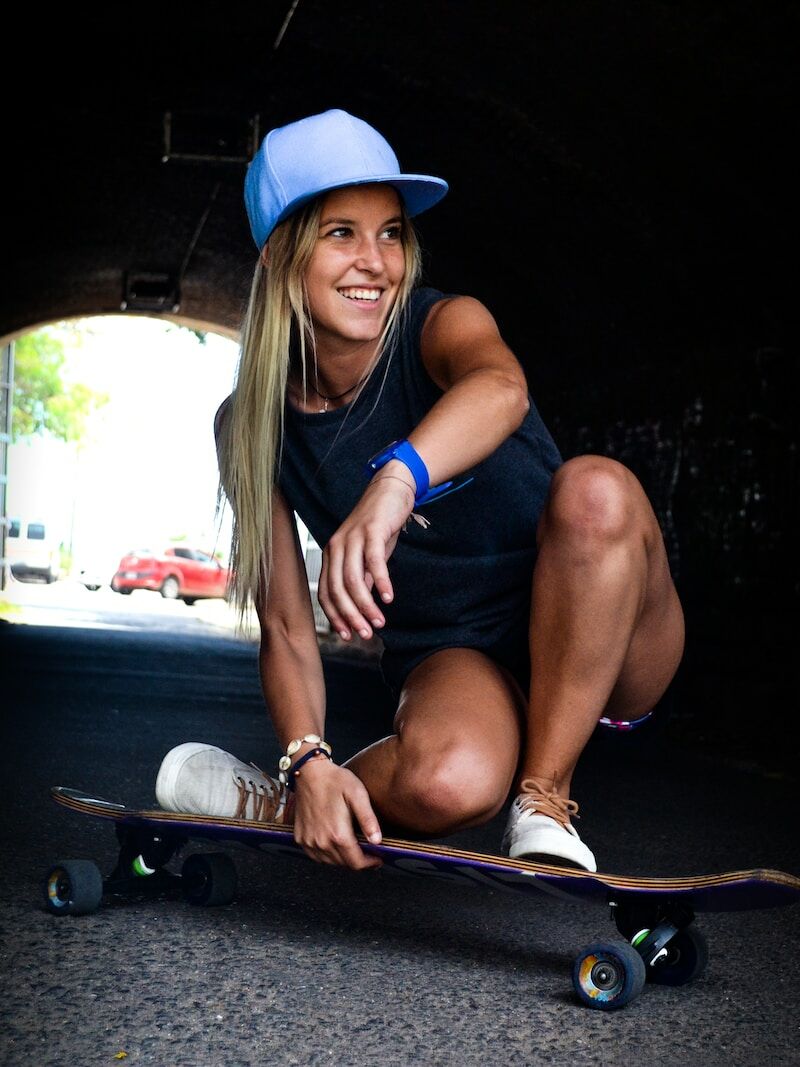 woman crouching while riding on skateboard during daytime shallow focus photography