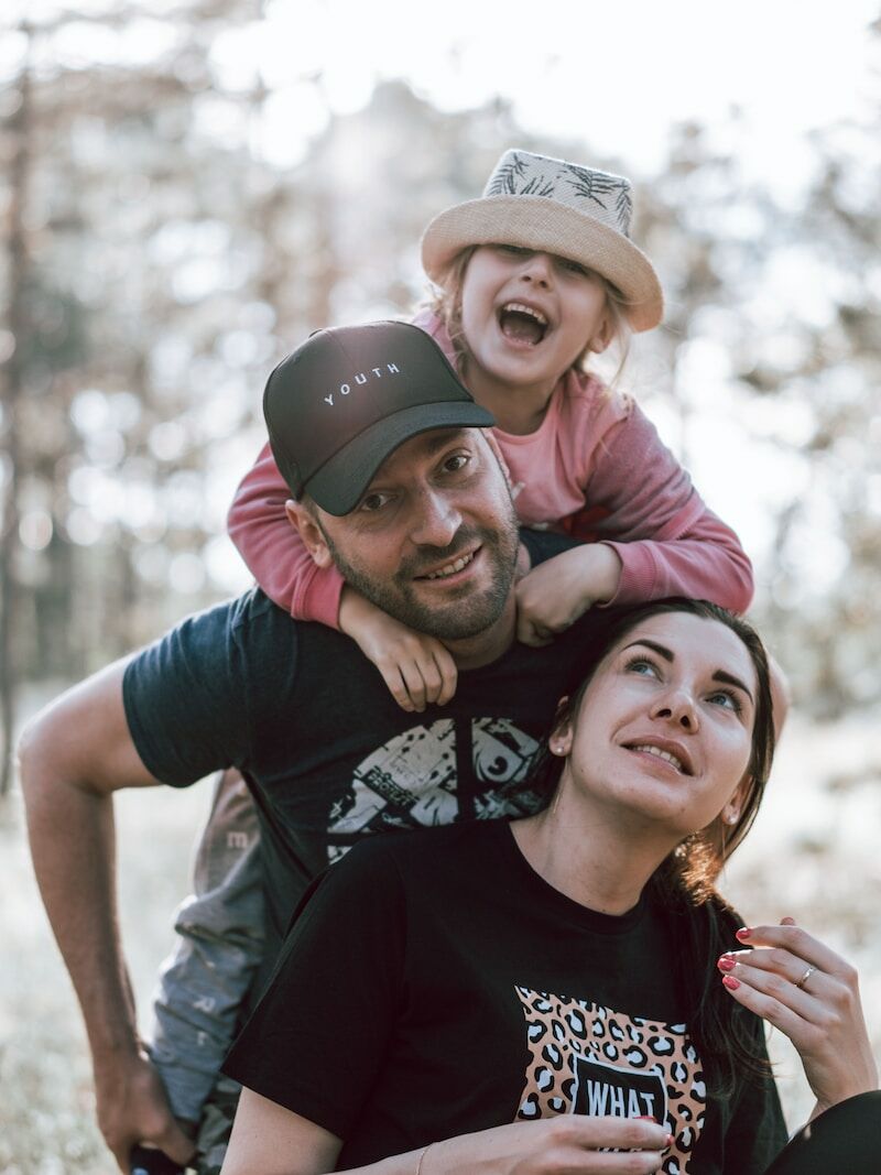 a man holding a little girl on his shoulders