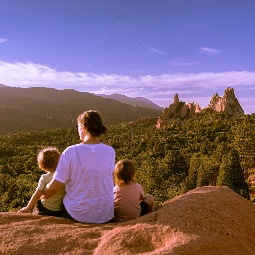 a man and two children sitting on top of a rock