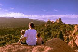 a man and two children sitting on top of a rock