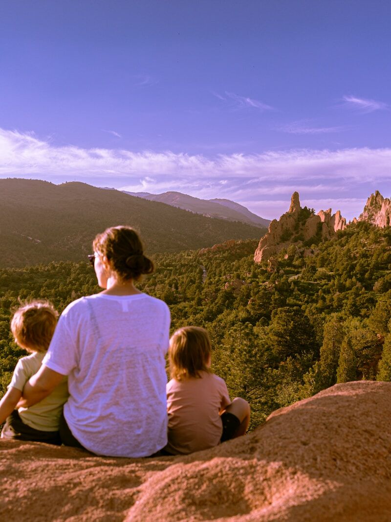 a man and two children sitting on top of a rock