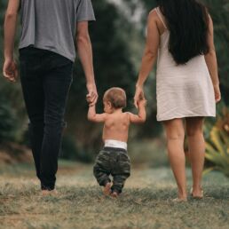 couple walking barefoot with a child at the garden