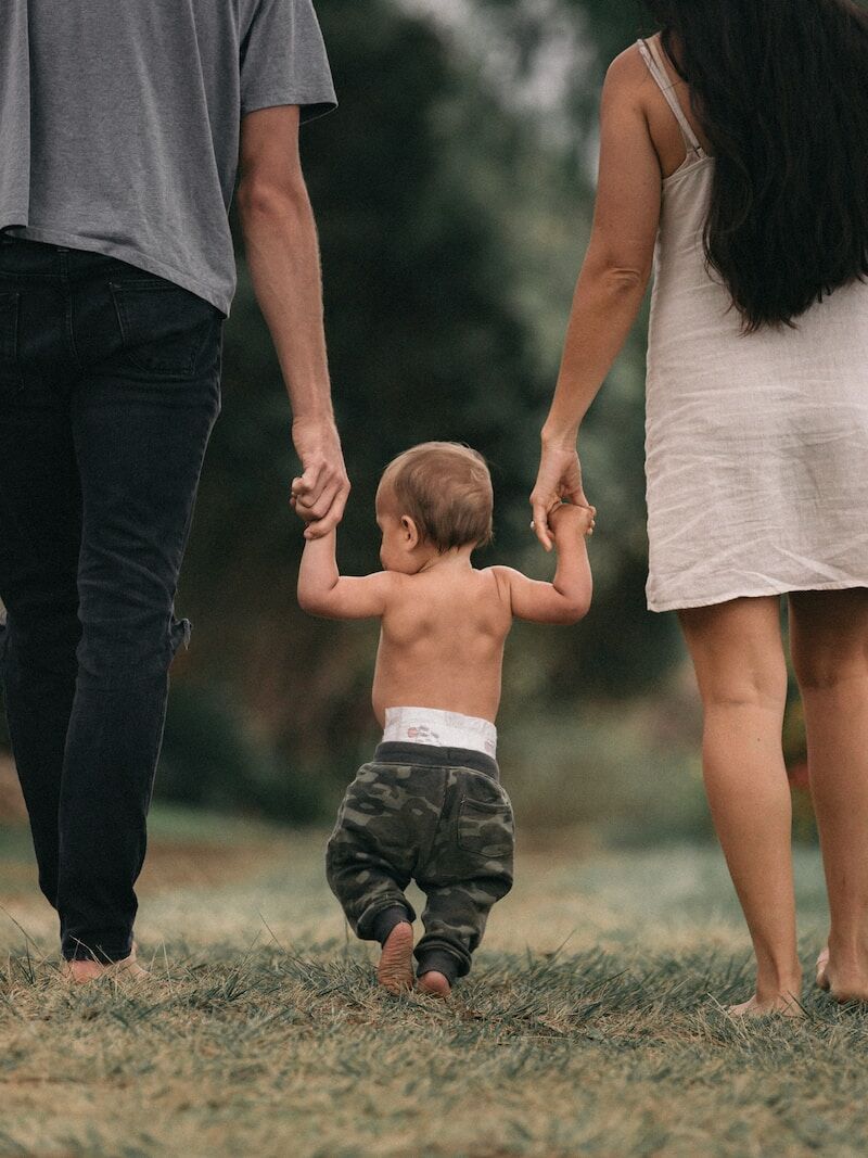 couple walking barefoot with a child at the garden