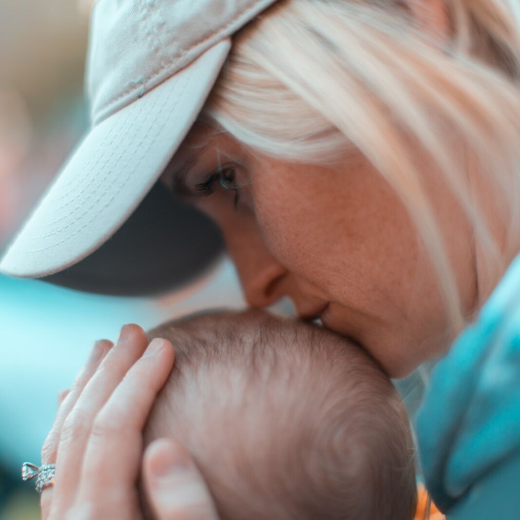 macro photography of woman kissing baby head