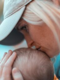 macro photography of woman kissing baby head