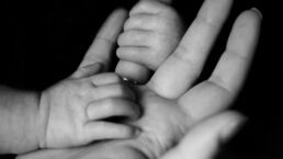 photo of baby holding person's fingers
