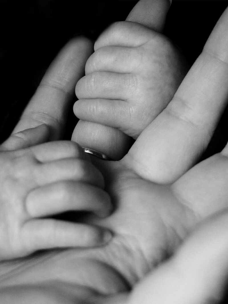 photo of baby holding person's fingers