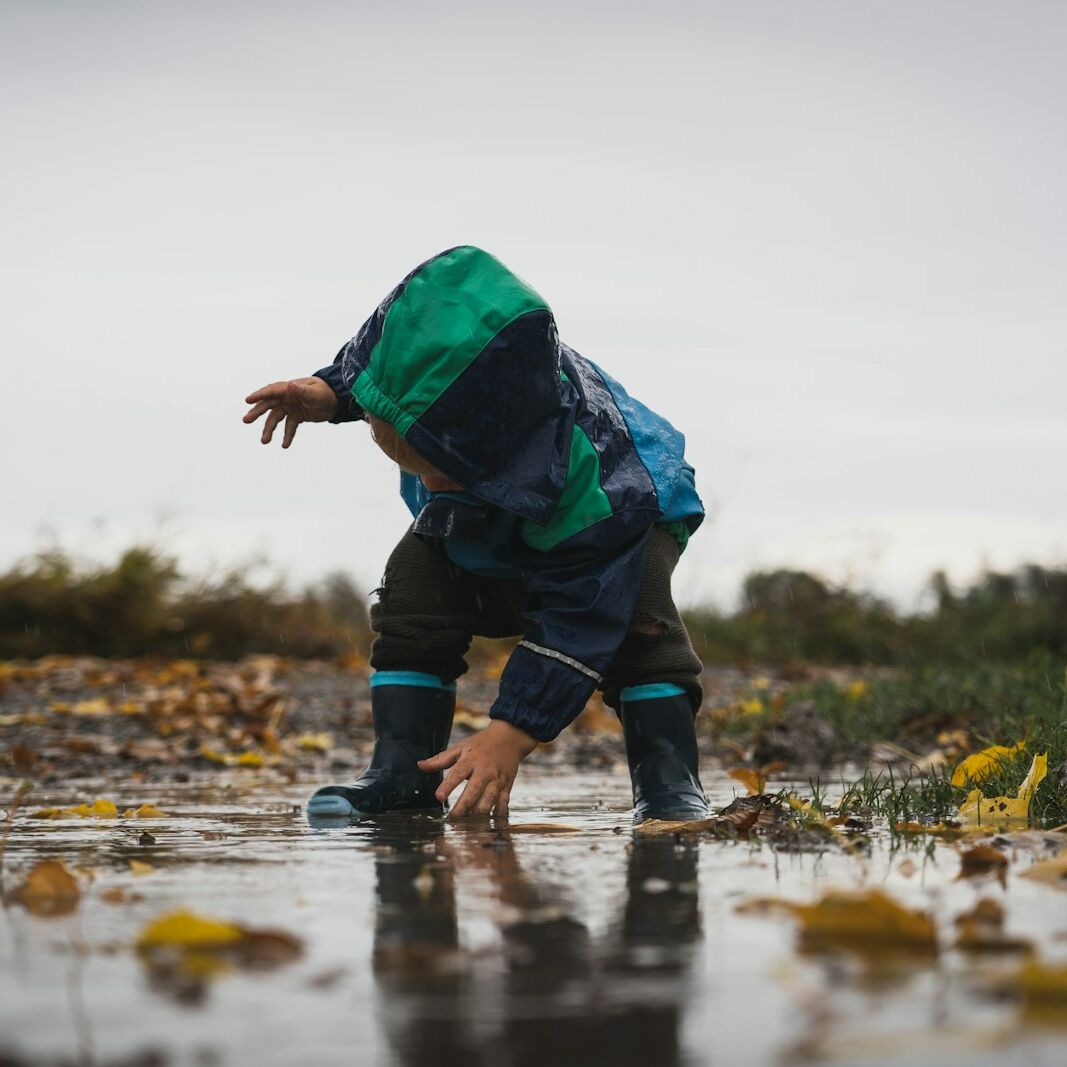 person in green jacket and black pants standing on water during daytime