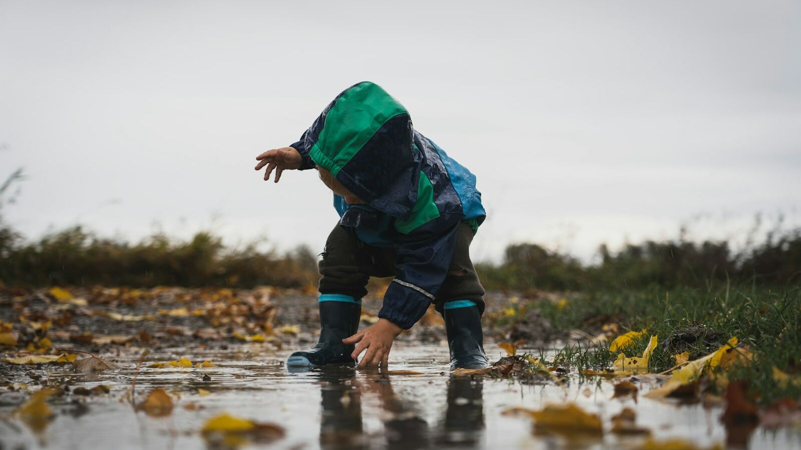 person in green jacket and black pants standing on water during daytime