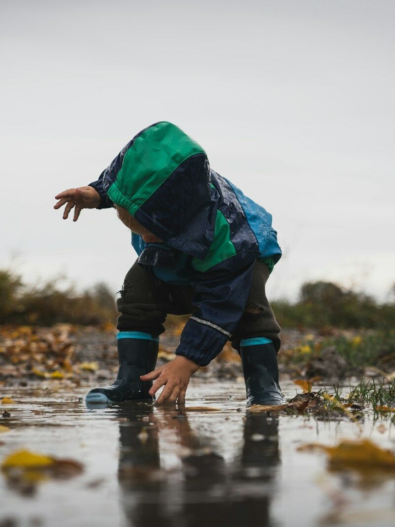 person in green jacket and black pants standing on water during daytime