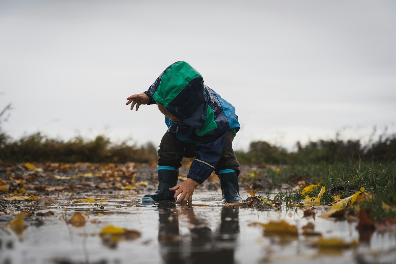 person in green jacket and black pants standing on water during daytime